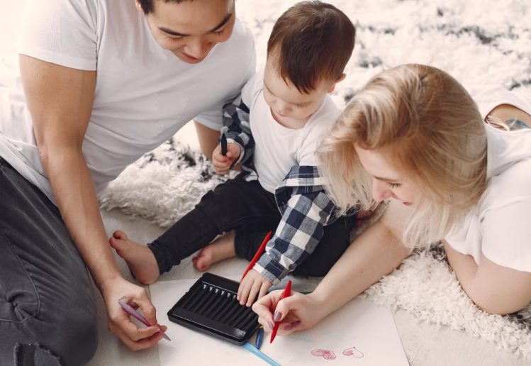 Parents and child enjoying drawing together on the floor, creating memories.