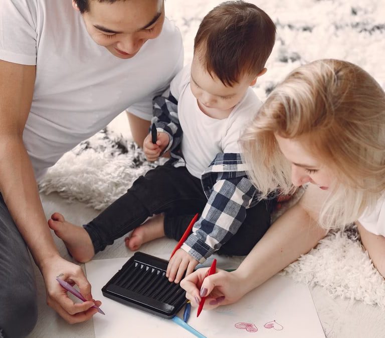 Parents and child enjoying drawing together on the floor, creating memories.